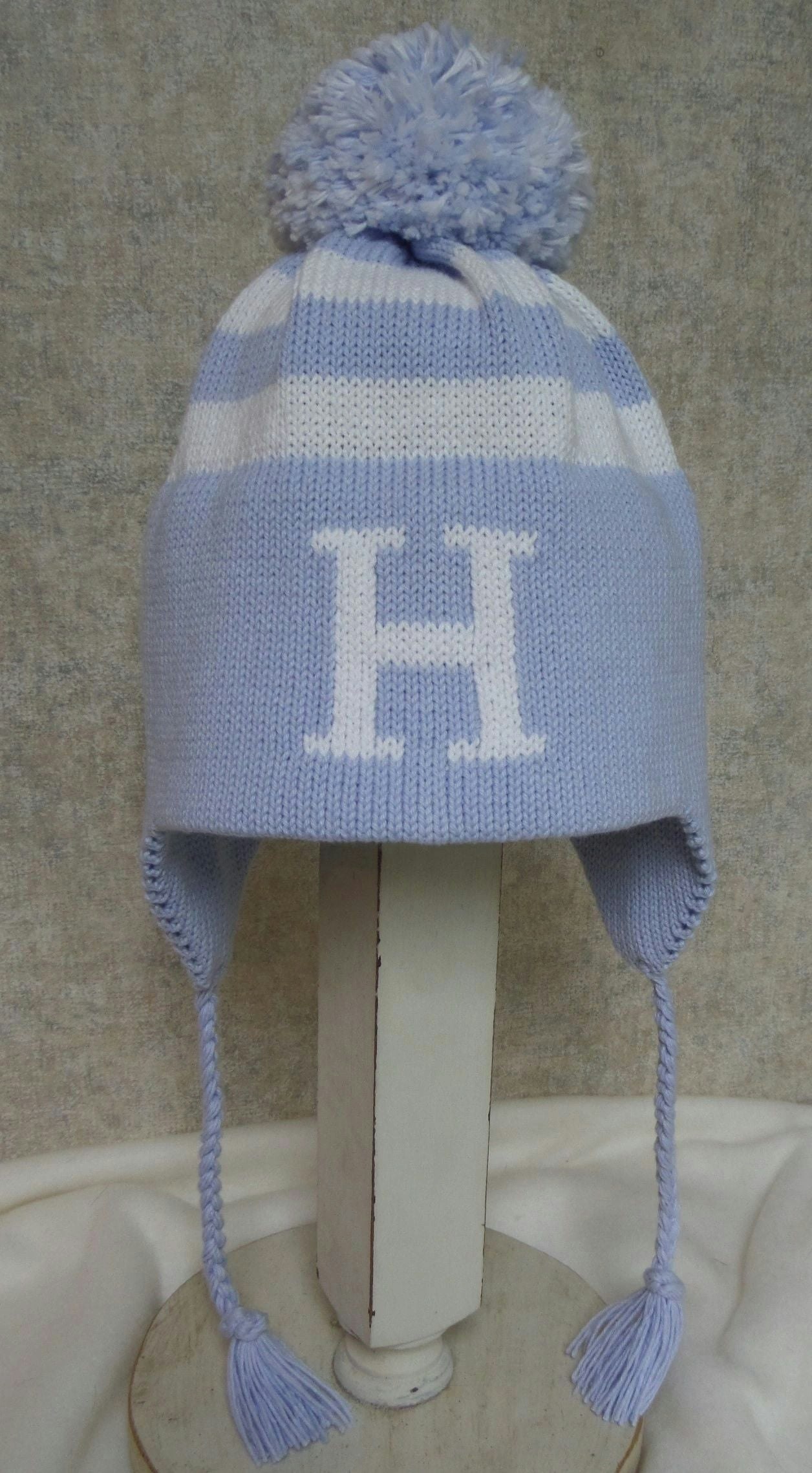 Stripe Earflap With Letter and Pompom - Product Hunt launch logo